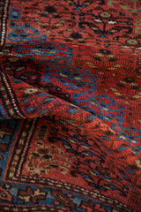 Hand-knotted texture of a vintage Kurd rug with red, blue, and brown geometric motifs.