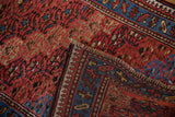 A Kurd rug's corner folded back to reveal the pawn motif border and hand-knotted foundation.