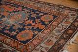 Vintage Persian Hamadan rug corner, showing navy field, copper florals, varied borders, and visible wear.