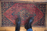 Stepped medallion and Herati design on a vintage Senneh rug in raspberry red and navy.
