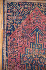 Vintage Senneh rug corner with navy spandrel, raspberry Herati motifs, and seed design border.