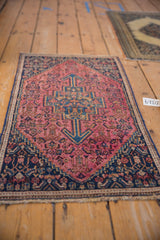 Vintage Senneh rug with navy blue stepped medallion and intricate raspberry Herati patterns.