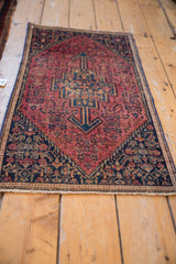 Close-up vintage Senneh mat: stepped medallion, arrowed finials, Herati motifs in raspberry red, navy.