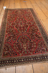 Sarouk rug close-up: dusty raspberry field with bursting floral bouquets and navy geometric border.