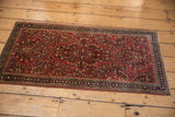 Sarouk runner's navy geometric border, dusty blush accents, raspberry floral field, visible knot heads.