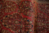 Hand-knotted pile showing curvilinear red, gold, navy floral pattern of a Sarouk rug.