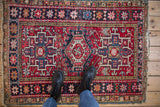Vintage Karaja rug corner, red and navy geometric patterns, pomegranate starburst border, worn fringe.