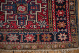 Vintage Karaja rug corner, pomegranate starburst border, geometric red, navy, ivory patterns, fringe.