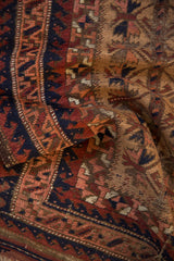 Hand-knotted pile with geometric motifs in camel, navy, and dusty apricot tones.