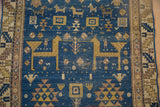 Geometric gold and ivory animal and herdsman motifs on deep sky blue field, showing wear.