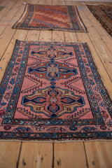 Vintage Mehriban rug's corner with geometric raspberry, sky blue, and terracotta patterns.