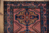 Worn side selvage, sapphire blue border, and geometric raspberry field of a vintage Mehriban rug.