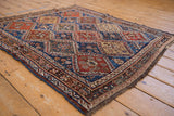 Angled view of an antique Qashqai rug's repeating panels with floral and pinwheel motifs.