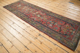 Worn red field of the Heriz runner, showcasing geometric florals, navy vinery, and evident mending.