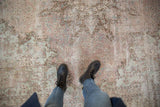 Distressed Kerman square carpet showing worn floral motifs in pale mauve and sea foam green.