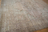 Distressed Kerman carpet's Rococo floral field and border, featuring pale mauve, sea foam green, and beige tones.