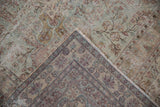 Folded Kerman carpet corner revealing back construction, distressed floral pile, and visible foundation.