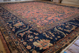 Vintage Mahal carpet detail: dusty rose field with blue floral motifs, navy border with scrolling leaves.