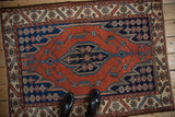 Upper corner of vintage Hamadan Maslaghan rug, featuring brick red field, serrated navy motifs, and ivory geometric border.