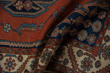 Folded vintage Hamadan rug detail, showing brick red, cobalt blue, and ivory Maslaghan serrated patterns.