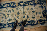 Peking rug corner: cobalt blue vine border, ivory field with contrasting leaves.