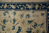 Vintage Peking rug: cobalt blue vine border, ivory field with green leaves, and pile wear.