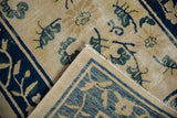 Detail of vintage Peking rug corner folded, showing continuous blue vine border and hand-knotted foundation.