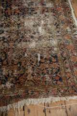 Threadbare areas and visible foundation on the vintage Hamadan rug's aged surface.
