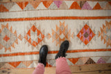 Textured distressed geometric pattern of a vintage Kurd runner with ivory, tangerine, and muted tones.