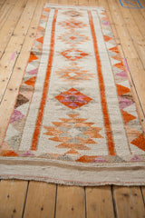 Distressed texture of a vintage Kurd runner, showing ivory, tangerine, and faded rust hues.