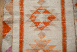Distressed Kurd rug runner, showing tangerine serrated gul medallion and worn texture.