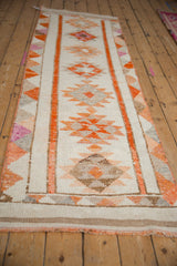 Distressed vintage Kurd runner featuring tangerine orange geometric triangle border and softened pile.