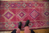 Overhead view of a distressed Kurd rug runner showing its textured, abrashed magenta and slate blue pattern.