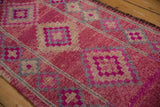 Evenly worn low pile on the abrashed magenta field of a vintage Kurd runner rug.