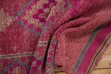 Folded vintage Kurd runner showing its distressed magenta pile and handwoven back construction.