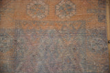 Textured Kurd rug pile showing even wear, pale tangerine and oxidized silver geometric blossoms.