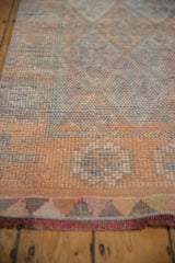 Distressed Kurd rug's textured pile, showing geometric patterns, tangerine, silver, and fringe.