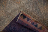 Muted silver distressed pile contrasts with vibrant geometric motifs on rug's folded edge.