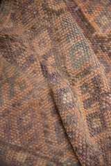 Close-up of the vintage distressed Kurd rug's textured pile, showing coffee brown and dusty mauve hues.