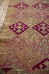 Deep fuchsia geometric blossoms with pale tangerine tones on heavily abrashed Kurd rug pile.