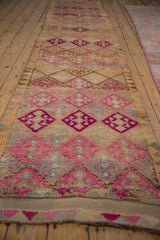 Vintage Kurd runner with fuchsia and tangerine geometric blossoms, showing pile wear.