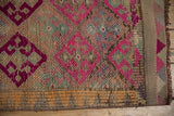 Side detail of a distressed Kurd runner, showing worn geometric fuchsia pattern and fringe.