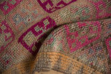 Textured close-up of Vintage Distressed Kurd rug, with fuchsia geometric blossoms.