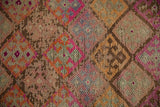 Distressed Kurd rug detail: geometric blossoms, knot heads, vibrant fuchsia, orange, and pale green.