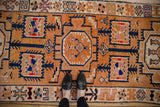 Vintage distressed Kurd runner with tangerine orange field, navy geometric vines, and short, even pile.