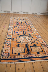Geometric germinating vines and motifs on distressed tangerine and navy Kurd rug.