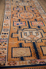 Distressed geometric motifs on a vintage Kurd runner, featuring tangerine, navy, and ivory tones.