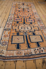 Decorative distressed Kurd runner, close-up geometric navy and tangerine orange motifs.