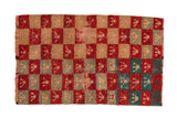 A distressed vintage Tulu rug with a shaggy checkerboard pattern of red, beige, and turquoise trefoil motifs.