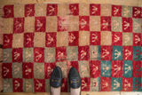 Distressed Tulu rug with a checkered pattern of red, ivory, and turquoise, shown for scale.